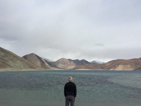 Man Traveler standing alone on cliff lake and foggy mountains on background Travel Lifestyle inspiring concept outdoor